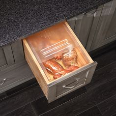 an open drawer in a kitchen with sausages and bread on the counter next to it