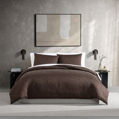 the bed is made with brown linens and white sheets, along with a painting on the wall