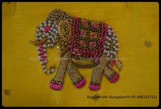 an elephant made out of beads on a yellow cloth with pink and white trims