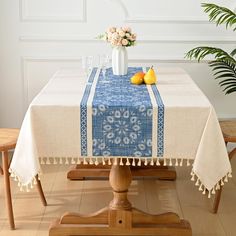 a blue and white table cloth with pom poms on it, sitting next to a potted plant