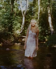 a woman is standing in the middle of a stream