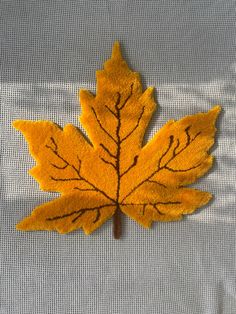 a yellow leaf with black lines on it sitting on a blue cloth covered tablecloth