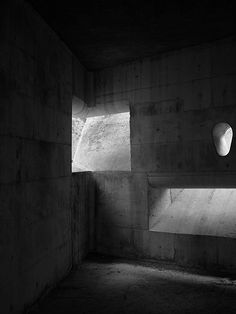 an empty concrete room with light coming through the window