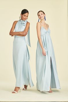 two women in blue dresses standing next to each other with their hands on their hips