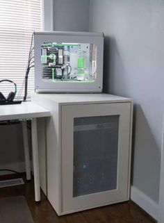 a white computer tower sitting on top of a wooden floor next to a window with blinds