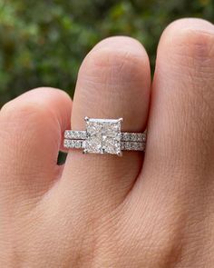 a woman's hand with a diamond ring on top of her finger and the other hand holding an engagement ring