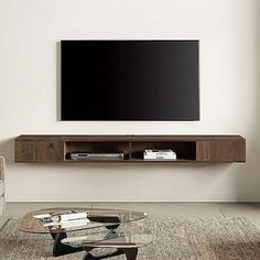 a living room with a large flat screen tv mounted on the wall above a glass coffee table