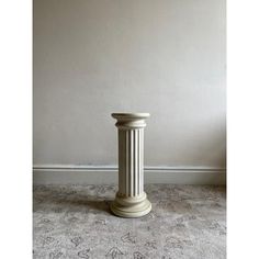 a tall white column sitting in the middle of a room next to a gray wall