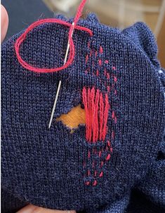 someone is stitching something on to a piece of fabric with needles and yarns