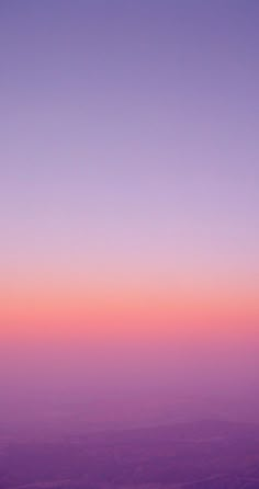 an airplane wing flying in the sky at sunset or dawn with pink and purple hues