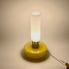 a yellow table lamp sitting on top of a white floor next to a light bulb