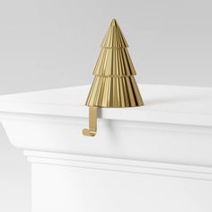 a gold christmas tree on the top of a white box with a metal hook in it