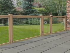 a wooden fence with wire on top and green grass in the back yard behind it