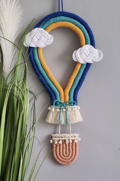 a wall hanging made out of rope and yarn with two clouds on the top, one in the shape of a heart