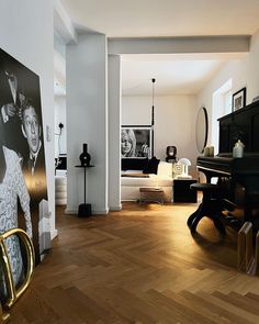 a living room filled with furniture and a piano in front of a painting on the wall