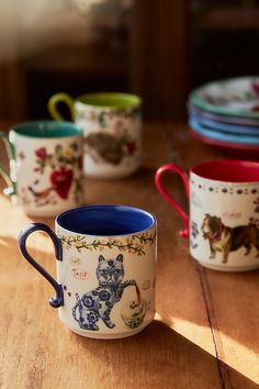 four coffee mugs sitting on top of a wooden table