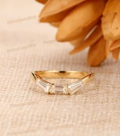 a gold ring with three baguettes sitting on a table next to some flowers