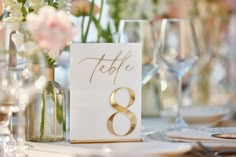 the table numbers are displayed in vases with flowers on them, along with wine glasses and napkins