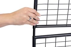 a person's hand holding onto the side of a black metal rack with two rings on it