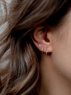 a close up of a woman's ear with two small diamond earrings on it