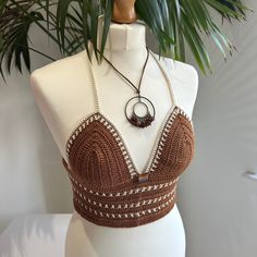 Handmade brown and beige Crochet Bralette Crop Top with adjustable tie back and glass bead embellishment. This top is made in a high quality beautiful brown yarn with beige details and features a fully adjustable halterneck tie, and a fully adjustable tie up back. It also features a bronze glass bead in the front center.  Due to its customisable nature, this top would fit someone between the sizes of UK 6/8 to UK14. Approximate cup size A - C. Displayed on a UK size 8/10 mannequin. Necklace not Fitted Brown Halter Top For Festivals, Festival Brown Crochet Lace Top, Bohemian Brown Crochet Top For Festival, Brown Crochet Beach Top, Brown Crochet Top For Beach, Beach Crochet Top In Brown, Beach Brown Crochet Top, Top Cafe, Brown Yarn