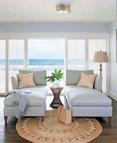 a living room with two couches and a rug in front of the window overlooking the ocean