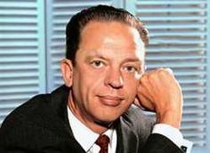 a man in a suit and tie sitting at a desk with his hand on his chin