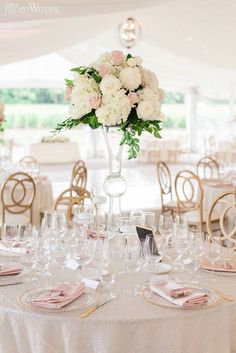 a table set up for a wedding reception with flowers in a tall vase on top