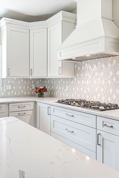 a kitchen with white cabinets and marble counter tops