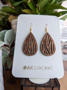 the earrings are made from wood and have zebra print designs on them, along with gold earwires