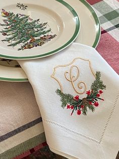 two christmas napkins on top of each other with embroidered monogrammed letters and holly wreath