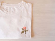 "Hand Embroidered women shirt with a flower. A beautiful t-shirt made of organic cotton. Discover its incredible soft touch and you will never want take it off. T-SHIRT DETAILS The sleeve is short and the neck is ribbed. SIZES: From XS to L (if you are looking for another one, ask me by message). It is an oversized t-shirt. The size of the photos is an S, it is not adjusted so I recommend you use the size you usually use or perhaps one less. The length is up to the hip approximately. You can che Luxury Embroidered Cotton T-shirt, Cheap Pink Embroidered T-shirt, Cheap Pink Floral Embroidered T-shirt, Flower T Shirt, Embroidered Designs, T Shirt Flowers, Slogan Tshirt, Customise T Shirt, Inspirational Shirt