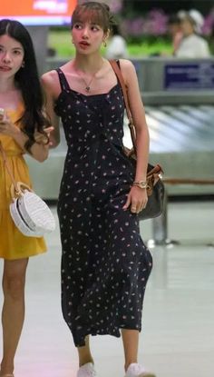 two young women are walking through an airport