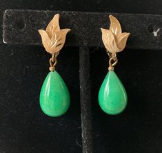 Pretty green glass teardrop dangle earring.  Classic style.  May be considered either jade green or Peking glass.   Each earring is accented by a small etched gold plated leaf on the ear lobe.  If you like an understated but sassy teardrop then you will love these swingy glowing earrings.  Some slight brushing on the top part of the clip.  (See view #7) Otherwise they, are in great condition. 1980s Dangle: 1 1/2"L  x  1/2"W Drop: 3/4" 12.2 grams wt. Attention: All items are listed to the best of our observation, but they are pre-owned and pre-loved (meaning we may have missed something minor and/or be in need of light cleaning.) Please read our shop policies and/or convo us before making your purchase. Have a shiny day! Shop item #8039 Green Teardrop Clip-on Earrings For Gift, Teardrop Jade Earrings For Formal Occasions, Vintage Green Jade Earrings, Green Teardrop Clip-on Earrings For Formal Occasions, Green Dangle Earrings Costume Jewelry, Green Dangle Costume Jewelry Earrings, Green Teardrop Dangle Earrings, Green Pierced Teardrop Dangle Earrings, Green Clip-on Dangle Jewelry