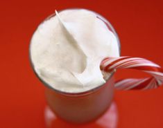 a candy cane sticking out of a cup filled with whipped cream