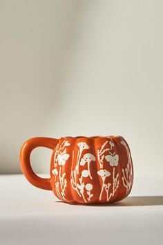 an orange coffee mug with white designs on the outside and inside is sitting on a table