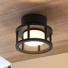 a close up of a light fixture on a wooden ceiling above a porch with wood planks