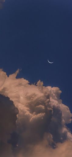 an airplane flying in the cloudy sky with a half moon on it's side