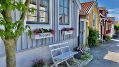 a bench sitting in front of a row of houses with flowers on the windows sill