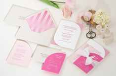 pink and white wedding stationery on display with flowers, scissors and other items for decoration