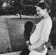 black and white photograph of a woman hugging a man on a bench in a park