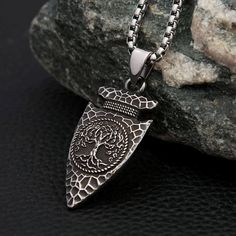 A fusion of Norse symbolism and Viking craftsmanship, designed to evoke the power and mystique of the ancient world. This exquisite necklace is more than just an accessory; it's a symbol of strength, wisdom, and the eternal connection between the realms of existence. At the heart of this captivating piece lies the Yggdrasil, the legendary World Tree, beautifully etched onto a spearhead pendant. The spearhead, a powerful symbol of protection and valor, pays homage to the mighty warriors of old, w Oxidized Stainless Steel Medallion Jewelry, Oxidized Stainless Steel Medallion Necklace, Nickel-free Spiritual Pendant Necklace, Spiritual Nickel-free Pendant Necklace, Symbolic Stainless Steel Jewelry With Large Pendant, Stainless Steel Large Pendant Necklaces, Spiritual Oxidized Medallion Jewelry, Oxidized Pendant For Meditation, Spiritual Metal Necklaces