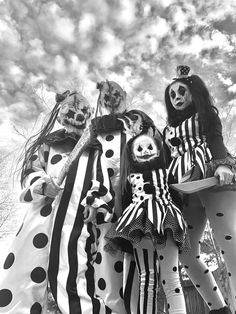 three women dressed up as clowns posing for a photo in front of the sky