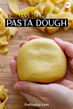 a person holding a doughnut in their hand with pasta on the table behind it