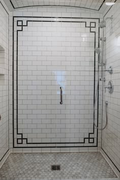 a white tiled shower with black trim around the door and shelves on the wall above it