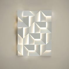 a white wall mounted sculpture on the side of a wall next to a light fixture