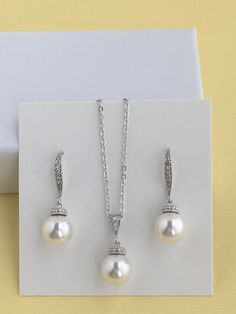 This classic pearl bridal jewelry set includes#Cubic zirconia and pearl bridal earrings in rhodium plated brass setting. Earrings feature 10mm Swarovski pearl drop that dangles from crystal encrusted ear wire. Total length of the earrings is 3 cms .#Classic pearl bridal necklace and pendant set with rhodium plated brass peg and bail. Necklace features a pendant with 10mm Swarovski single pearl drop that dangles from rhodium plated brass peg and cubic zirconia bail. Length of the rhodium plated c Formal Pearl Drop Jewelry Sets With Cubic Zirconia, Classic White Jewelry Sets For Wedding, Anniversary Jewelry Sets With Pearl Drop And Cubic Zirconia, Silver Jewelry Sets With Pearl Drop For Formal Occasions, Classic Sterling Silver Jewelry Sets For Wedding, Classic Silver Jewelry Sets With Pearl Drop, Silver Jewelry Sets With Pearl Pendant For Formal Events, Silver Jewelry Sets With Pearl Pendant For Formal Occasions, Classic Bridal Earrings With Pearl Pendant For Wedding