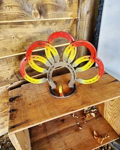 a wooden bench with a metal sculpture on it's back and yellow flowers in the center