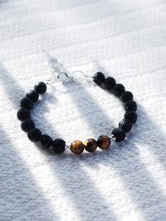 This Tigers Eye and Lava bracelet is sure to become an everyday staple. Tigers eye promotes inner strength and was once considered more precious than gold. Part of our Men's Collection, but designed to be gender inclusive, this unique bracelet is a classic staple.✦ DETAILS ✦✧ Name: Ekewaka (eh-keh-WAH-kah) - The protector or guardian of riches or wealth.✧ Genuine Tigers Eye beads .✧ 8mm Lava Beads.✧ Sterling silver components.✧ All Ke Aloha Jewelry pieces come packaged thoughtfully, beautifully, Spiritual 8mm Beads Jewelry For Everyday, Minimalist Bracelets With 8mm Beads For Healing, Minimalist Gemstone Beads Bracelets For Meditation, Minimalist 8mm Bead Bracelet Jewelry, Minimalist 8mm Bead Bracelet, Spiritual Round Bracelets For Everyday, Everyday Round Spiritual Bracelets, Everyday Spiritual Round Bracelets, Everyday Spiritual Bangle Bracelet