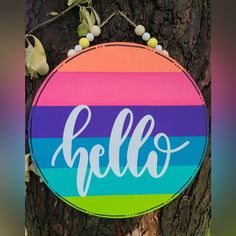 a colorful sign that says hello hanging on a tree